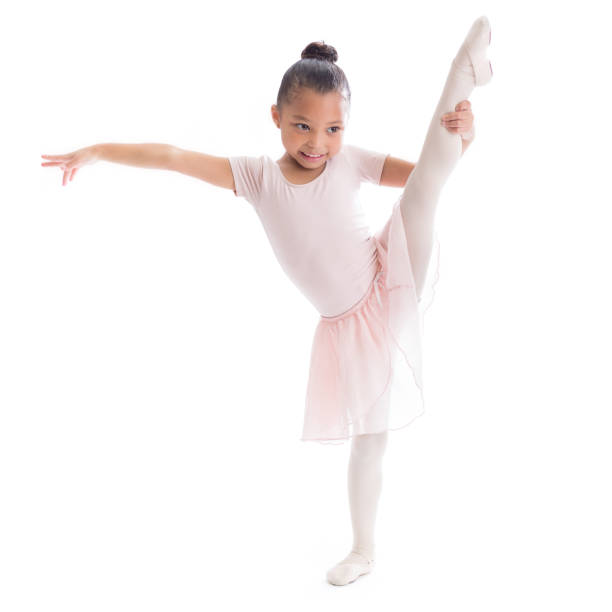 Cute preschool age African American female ballerina stretches out her leg in ballet pose.